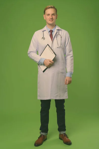 หมอหนุ่มหล่อผมบลอนด์กับพื้นหลังสีเขียว — ภาพถ่ายสต็อก
