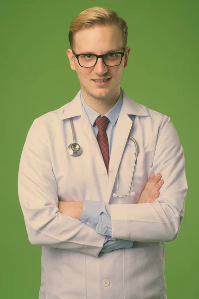 Joven hombre guapo médico con el pelo rubio sobre fondo verde —  Fotos de Stock