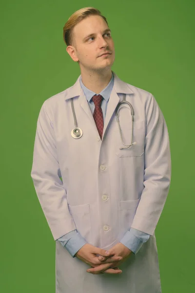 Jovem médico homem bonito com cabelo loiro contra fundo verde — Fotografia de Stock