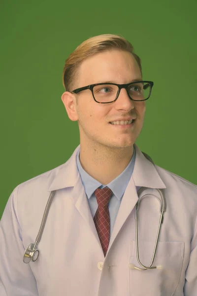 Jovem médico homem bonito com cabelo loiro contra fundo verde — Fotografia de Stock