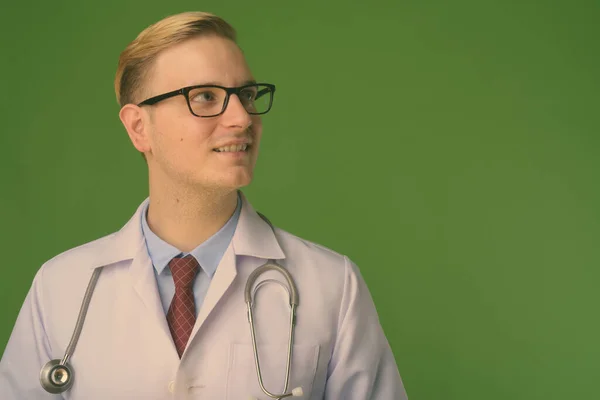 Jonge knappe man arts met blond haar tegen groene achtergrond — Stockfoto
