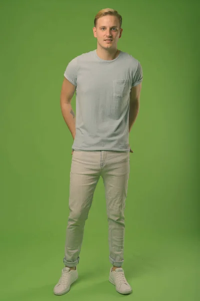 Jovem homem bonito com cabelo loiro contra fundo verde — Fotografia de Stock