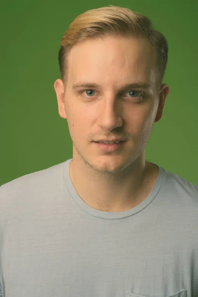Młody przystojny mężczyzna z blond włosy na zielonym tle — Zdjęcie stockowe