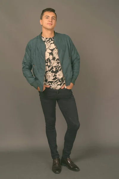 Studio shot of young handsome man against gray background — Stock Photo, Image