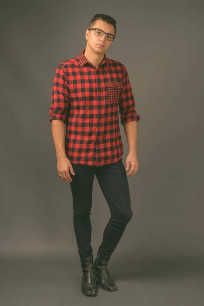 Studio shot of young handsome man against gray background — Stock Photo, Image