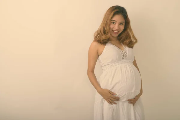Studio plan de jeune femme enceinte asiatique heureuse souriant sur fond blanc — Photo