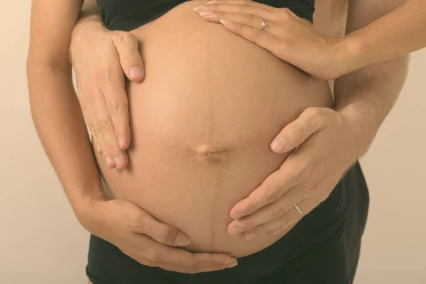 Zbliżenie młodej Azjatki w ciąży z mężczyzną trzymającym jej żołądek razem jako symbol rodzicielstwa na białym tle — Zdjęcie stockowe