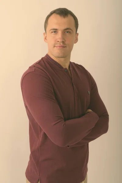 Studio shot of young muscular man with arms crossed against white background — Stock Photo, Image