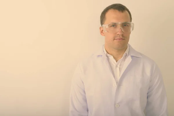 Studio shot de jeune homme musclé médecin portant des lunettes de protection sur fond blanc — Photo