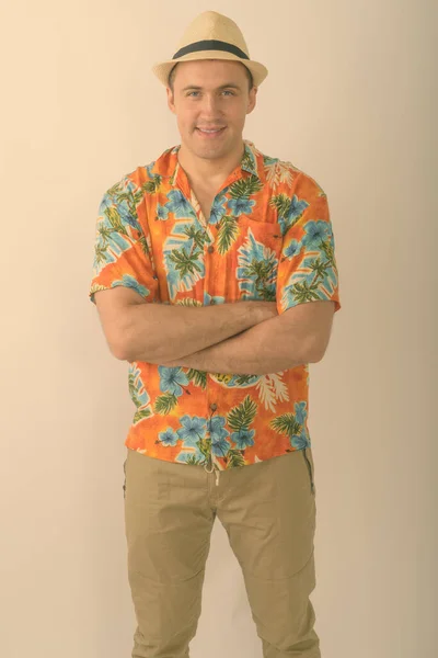 Studio shot of young happy muscular tourist man smiling and standing with arms crossed against white background — Stock Photo, Image