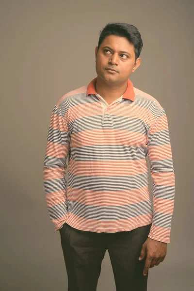 Portret van jonge knappe Indiase man tegen studioachtergrond — Stockfoto
