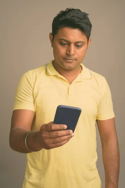 Portrait of young handsome Indian man against plain studio background — Stock Photo, Image