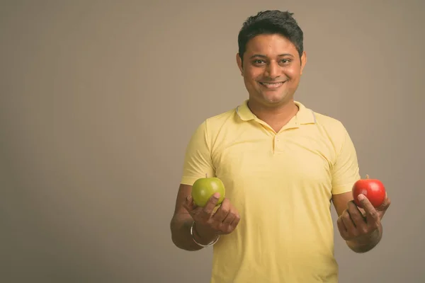 Portrait of young handsome Indian man against plain studio background — Stock Photo, Image