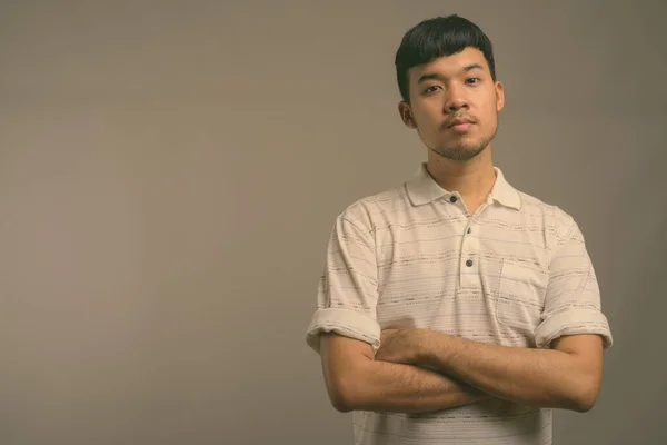 Retrato de jovem asiático contra fundo cinza — Fotografia de Stock