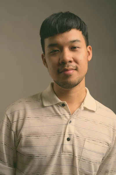 Gri arka planda Asyalı genç bir adamın portresi — Stok fotoğraf