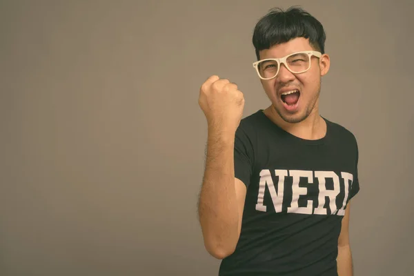 Young Asian nerd man wearing eyeglasses against gray background — Stock Photo, Image