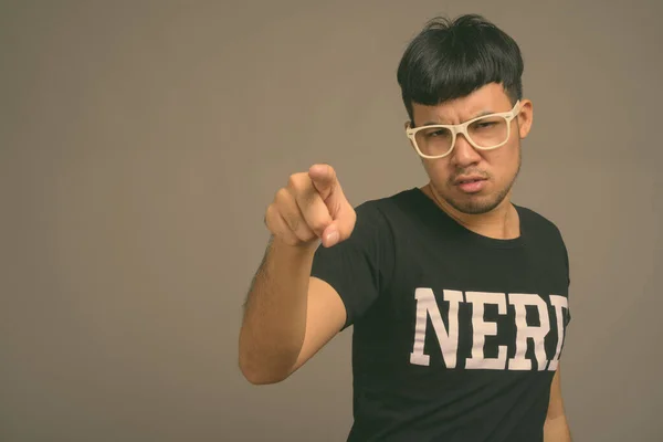 Joven asiática nerd hombre usando anteojos contra gris fondo —  Fotos de Stock