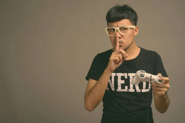 Junger asiatischer Nerd mit Brille vor grauem Hintergrund — Stockfoto