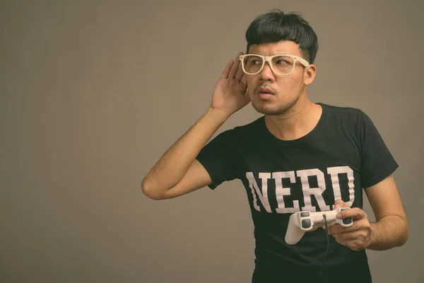 Junger asiatischer Nerd mit Brille vor grauem Hintergrund — Stockfoto