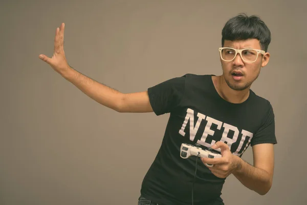 Joven asiática nerd hombre usando anteojos contra gris fondo —  Fotos de Stock