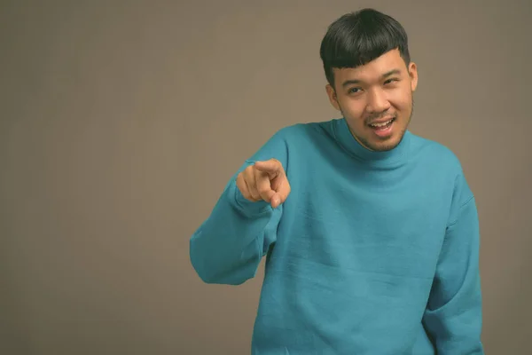 Portrait of young Asian man against gray background — Stock Photo, Image