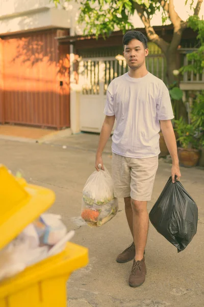 Jovem ásia homem tomando fora o lixo no casa — Fotografia de Stock