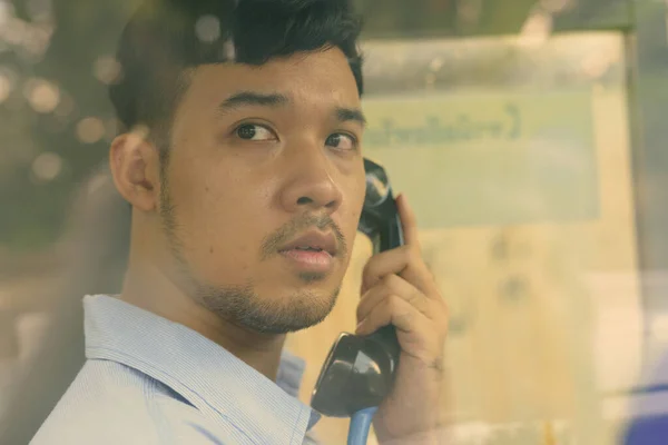 Jovem empresário asiático usando o telefone público ao ar livre — Fotografia de Stock