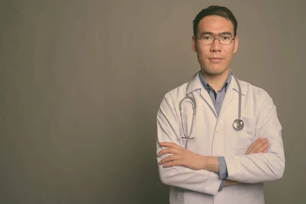 Joven asiático hombre médico contra gris fondo —  Fotos de Stock