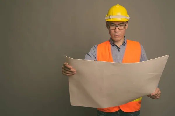 Joven asiático hombre construcción trabajador contra gris fondo —  Fotos de Stock