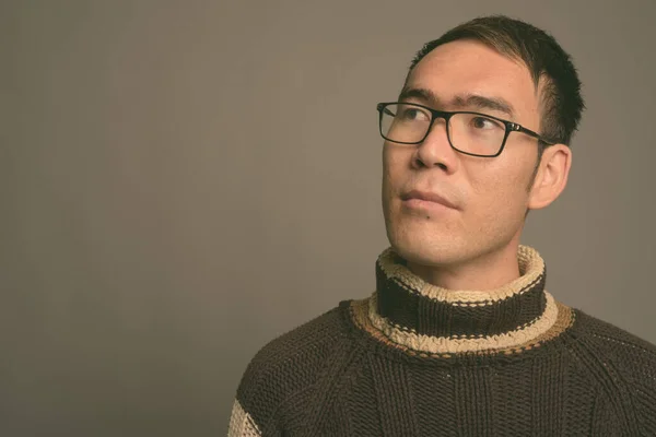 회색 바탕에 터틀넥 스웨터를 입고 있는 아시아 청년 — 스톡 사진