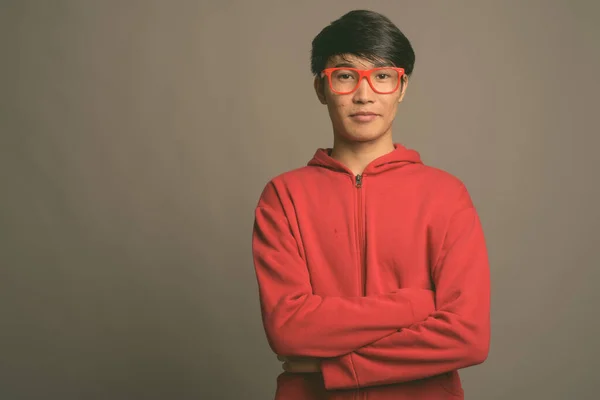 若いですアジアの男身に着けています赤いジャケットで眼鏡でグレーの背景 — ストック写真