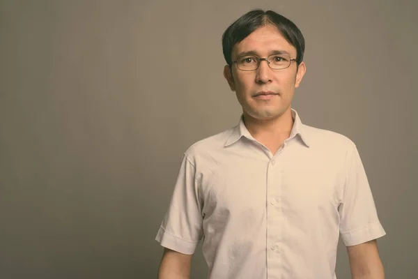 Joven asiática nerd hombre usando anteojos contra gris fondo —  Fotos de Stock