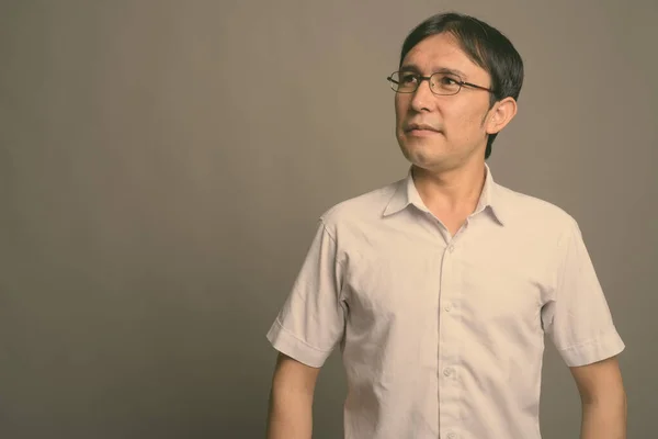 Young Asian nerd man wearing eyeglasses against gray background — Stock Photo, Image