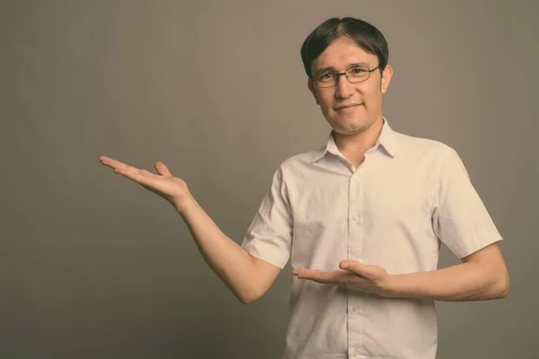 Joven asiática nerd hombre usando anteojos contra gris fondo —  Fotos de Stock