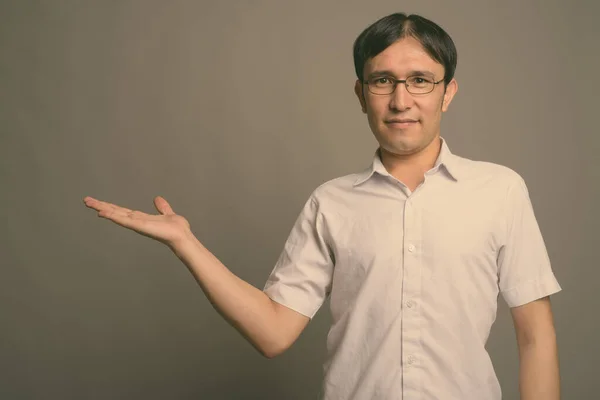 Joven asiática nerd hombre usando anteojos contra gris fondo —  Fotos de Stock