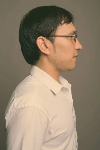 Юнак з Азії, який носить окуляри на сірому фоні. — стокове фото