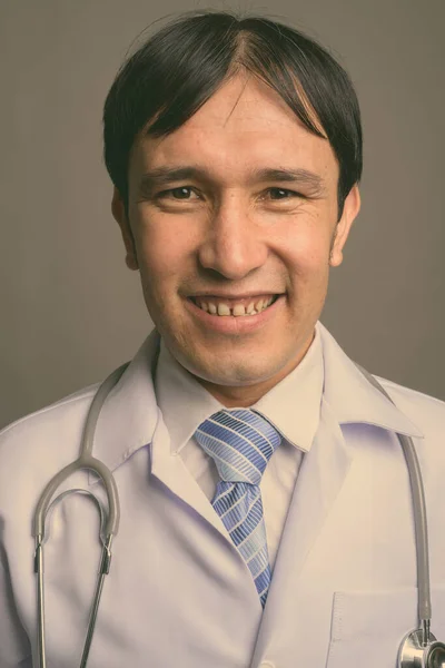 Giovane asiatico uomo medico contro grigio sfondo — Foto Stock