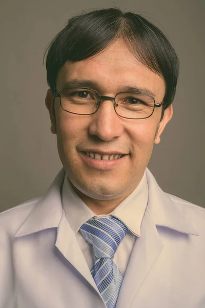 Fiatal ázsiai férfi orvos visel szemüveg ellen szürke háttér — Stock Fotó