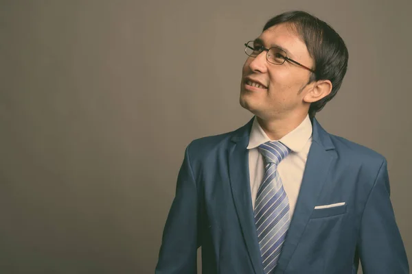 Young Asian businessman against gray background — Stock Photo, Image