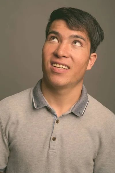 Young Asian man against gray background — Stock Photo, Image