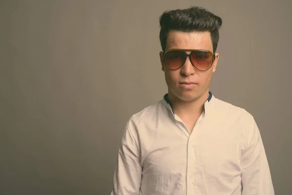 Ung asiatisk affärsman bär solglasögon mot grå bakgrund — Stockfoto