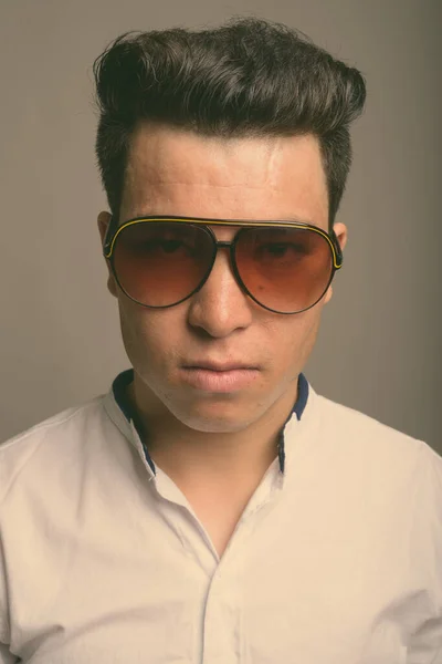 Młody azjatycki biznesmen w okularach przeciwsłonecznych na szarym tle — Zdjęcie stockowe