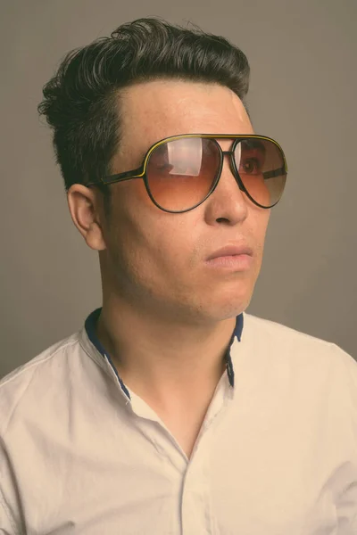 Ung asiatisk affärsman bär solglasögon mot grå bakgrund — Stockfoto