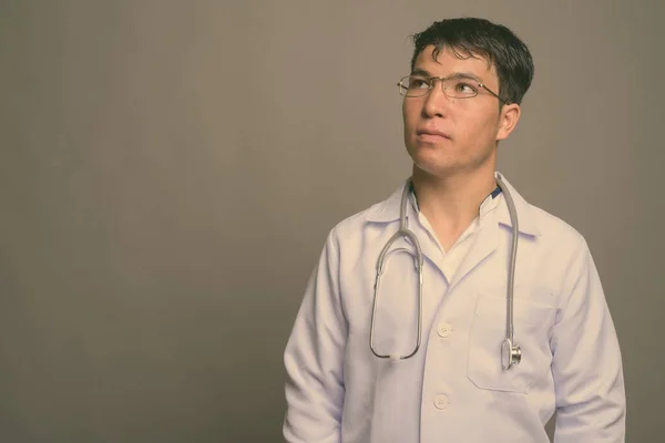 Joven asiático hombre médico contra gris fondo —  Fotos de Stock