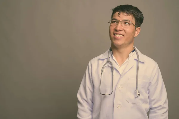 Joven asiático hombre médico contra gris fondo —  Fotos de Stock