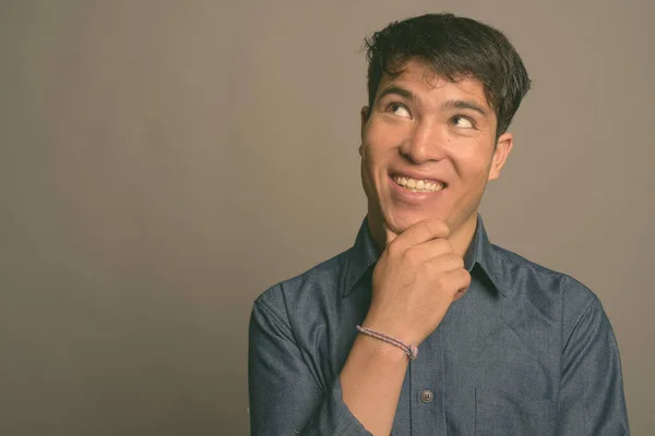 Ung asiatisk man bär blå skjorta mot grå bakgrund — Stockfoto