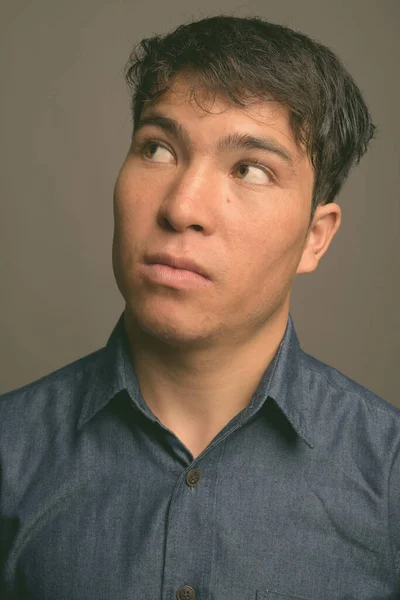 Joven asiático vistiendo camisa azul sobre fondo gris — Foto de Stock