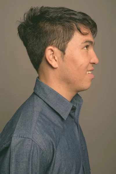 Молодий азіатський чоловік у синій сорочці на сірому фоні. — стокове фото
