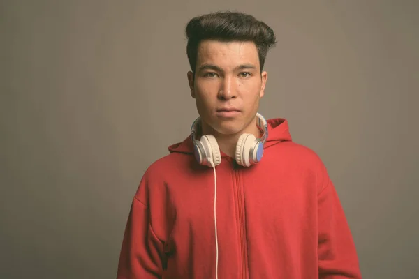 Młody Azjata nosi słuchawki na szarym tle — Zdjęcie stockowe