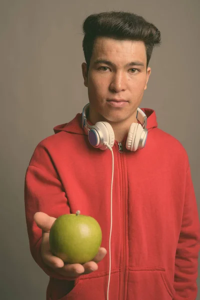 회색 배경에 헤드폰을 끼고 있는 아시아 청년 — 스톡 사진